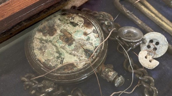 Un ceas de buzunar și nasturii care au fost găsiți împreună cu corpul sergentului adjunct Charles Stevens