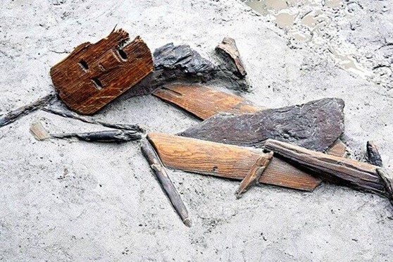 Alături de masca rituală, arheologii au mai descoperit o găleată de apă din lemn și o sapă de grădinărit.