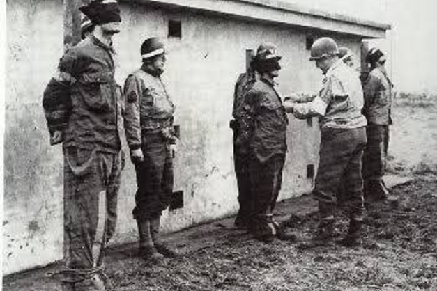Un grup de germani ce fuseseră capturați purtând uniforme americane sunt executați în timpul Bătăliei de la Bulge